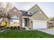 Charming home featuring a brick facade, green siding, attached garage, and manicured landscaping at 10775 Northhampton Dr, Fishers, IN 46038