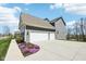 Side view of a gray home featuring a three-car garage and well-maintained landscaping at 14413 Arnett Dr, Carmel, IN 46033