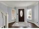 Bright foyer with hardwood floors, decorative rug, and dark wood door flanked by windows allowing natural light at 1444 Trail Creek Ct, Carmel, IN 46032