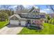 Inviting two-story green home featuring a three-car garage, well-manicured lawn, and charming front porch at 15385 Ellington Dr, Fishers, IN 46040