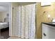 Bathroom with polka-dot shower curtain, tan wall paint, and cabinet with black countertop at 15501 Landsbrook E Run, Noblesville, IN 46060