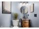 Powder room with a round mirror, three-light vanity lighting, and a grey-painted vanity at 1583 E Osprey Dr, Greenfield, IN 46140