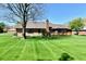 Spacious backyard with lush green grass, mature trees, and a brick home with back deck at 1927 Pheasant Way, Greenwood, IN 46143