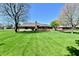 Well-maintained backyard with a lush lawn, mature trees, and a charming brick home with a deck at 1927 Pheasant Way, Greenwood, IN 46143