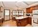 Eat-in kitchen features wood cabinets, laminate floors, breakfast bar, and sunny windows with lace curtains at 1927 Pheasant Way, Greenwood, IN 46143