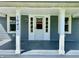 Inviting covered front porch with white columns, updated flooring, and a bright front door at 1942 E Edgewood Ave, Indianapolis, IN 46227