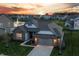 Stunning home with manicured lawn, gray brick, gray siding, 2-car garage and community pond view at sunset at 20515 Quicksilver Rd, Noblesville, IN 46062