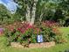 Gorgeous front yard with brick-lined garden bed filled with bright pink roses, tree, and Colts sign adding character at 3155 W 57Th St, Indianapolis, IN 46228