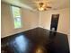 Bedroom with white walls, ceiling fan, and dark hardwood floors with a window and black door at 404 W Green St, Lebanon, IN 46052