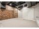 Finished basement featuring exposed brick wall, neutral carpeting, and bright lighting at 4151 N Pennsylvania St, Indianapolis, IN 46205