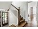 Elegant stairway with wooden steps and white railing, next to the entry door at 4151 N Pennsylvania St, Indianapolis, IN 46205