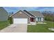 Charming single-story home boasts a well-maintained lawn, attached garage and inviting red front door at 4323 Stubbington Ln, Indianapolis, IN 46239