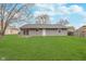 A level backyard with a gray-sided house, mature trees, and a well-maintained lawn at 4326 Burrwood Dr, Indianapolis, IN 46235