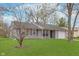 A single-story home with an attached garage is framed by mature trees and a green lawn at 4326 Burrwood Dr, Indianapolis, IN 46235