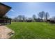 Large, grassy backyard with a storage shed and mature trees on a sunny day at 4329 Dudley N Dr, Indianapolis, IN 46237