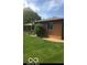 Backyard with brick home exterior, landscaped with green lawn and bushes at 4329 Dudley N Dr, Indianapolis, IN 46237