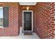 Close-up of a solid front door with brick surround, decorative plants and a welcome mat, creating a charming entrance at 4638 W Otway Ln, New Palestine, IN 46163
