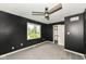 Modern bedroom with dark walls, plush carpet, ceiling fan and a bright window view at 5302 E 46Th St, Indianapolis, IN 46226