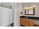 Well-lit bathroom features vanity with dark granite countertop, wooden cabinets, a shower-tub combo, and modern fixtures at 55 S Harding St # 301, Indianapolis, IN 46222