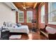 Bedroom showcases exposed brick walls, hardwood floors, a ceiling fan, and bright natural light through two large windows at 55 S Harding St # 301, Indianapolis, IN 46222