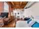 Bedroom boasts exposed brick, hardwood floors, a ceiling fan, and ample sunlight through multiple windows at 55 S Harding St # 301, Indianapolis, IN 46222