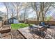 Spacious backyard with a wooden deck, outdoor seating, storage shed, playset, and lush green grass at 5619 Carrollton Ave, Indianapolis, IN 46220