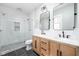 Modern bathroom featuring a double sink vanity, sleek tile flooring, and a glass-enclosed shower with white subway tile at 5619 Carrollton Ave, Indianapolis, IN 46220
