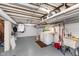Unfinished basement laundry area with exposed pipes and painted concrete walls, utility sink, and washer/dryer at 5942 Primrose Ave, Indianapolis, IN 46220
