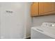 Bright laundry room featuring overhead cabinets, a washer, utility hook, and a white painted wall at 6846 Emerald Bay Ln, Indianapolis, IN 46237