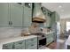Custom kitchen featuring sage green cabinetry, stainless appliances, stylish backsplash and hood vent at 706 E 750 N, Lebanon, IN 46052
