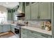 Custom kitchen featuring sage green cabinetry, stainless appliances, stylish backsplash and hood vent at 706 E 750 N, Lebanon, IN 46052