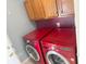Convenient laundry area with bright red washing machines and storage cabinets for supplies at 7201 Barnwell Pl, Indianapolis, IN 46217