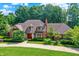 Beautiful brick home featuring a red door, manicured landscaping, and mature trees at 7545 Chablis Cir, Indianapolis, IN 46278