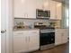 Close-up of the kitchen, showcasing modern appliances, white cabinetry, and granite countertops at 7636 Big Bend Blvd, Camby, IN 46113