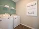 Well-lit laundry room with modern washer and dryer units, and convenient overhead shelving for storage at 7636 Big Bend Blvd, Camby, IN 46113