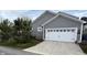 Attached two car garage with white door and grey siding, nestled in mature landscaping and private driveway at 7638 Beekman Ter, Zionsville, IN 46077