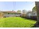 Spacious backyard with lush green grass, wooden deck, privacy fence, and mature trees offering shade at 7735 E 50Th St, Indianapolis, IN 46226