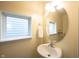 Charming powder room with a pedestal sink, oval mirror, and natural light at 1099 Valentine Ln, Carmel, IN 46032