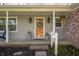 A covered front porch with stylish decor, including wall lanterns, plants, and a welcome wreath at 1109 Oakwood Trl, Indianapolis, IN 46260
