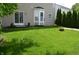 A lush green backyard with a sliding glass door, bay window, and privacy provided by a row of tall evergreen trees at 12326 River Valley Dr, Fishers, IN 46037