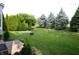 Manicured backyard with lush green grass, mature trees, stepping stones, and a charming fire pit at 12326 River Valley Dr, Fishers, IN 46037