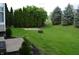 Spacious backyard with lush grass, a fire pit area, privacy trees, and a small patio area perfect for outdoor gatherings at 12326 River Valley Dr, Fishers, IN 46037