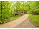 View of a long driveway leading to a house with a large wooden deck and lush trees in the background at 13306 W 50 S, Columbus, IN 47201