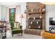 Living room featuring a brick fireplace, green armchairs, and a large window with natural light at 13306 W 50 S, Columbus, IN 47201