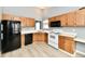 Kitchen with wood cabinets, white appliances, and wood-look floors at 1632 Blankenship Dr, Indianapolis, IN 46217
