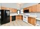 Kitchen with wood cabinets, white appliances, and wood-look floors at 1632 Blankenship Dr, Indianapolis, IN 46217