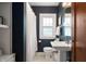 Stylish bathroom with dark blue walls, white fixtures, pedestal sink, and a window with decorative glass at 171 W 44Th St, Indianapolis, IN 46208