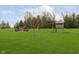 Backyard featuring a wooden swing set and slide surrounded by green grass at 180 S 400 W, Lebanon, IN 46052
