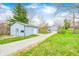 Wide shot of a charming home and shed on a sprawling lot with a gravel driveway, blending natural beauty at 1907 N Washington St, Danville, IN 46122