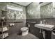 Modern bathroom with leafy green wallpaper, tile wainscoting, white fixtures, and accessibility support bars at 2329 Shelby St, Indianapolis, IN 46203